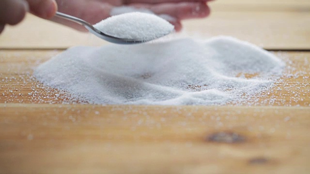 手拿勺子从木桌上的糖堆里取糖视频素材