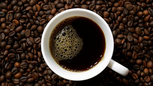 白杯子里的黑咖啡，堆在一堆烘好的咖啡豆上视频下载