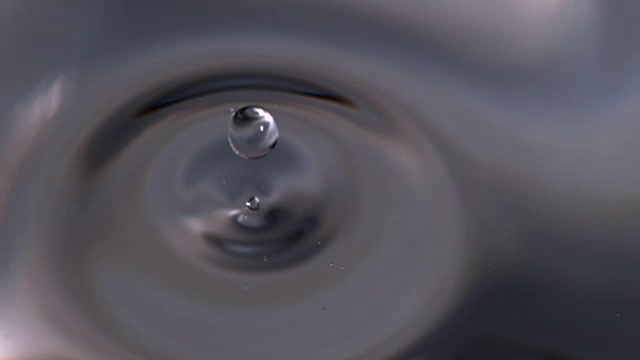 慢动作近景水滴落入玻璃烧杯的水。视频素材