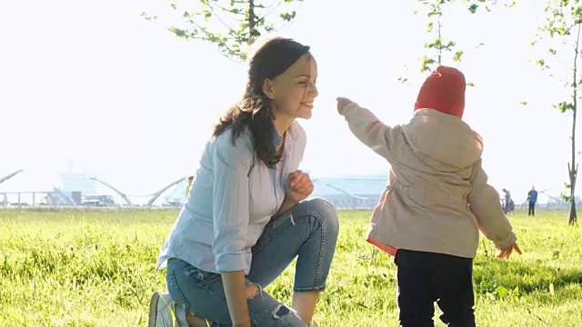 母亲和孩子在嗅植物。快乐的年轻家庭在公园散步视频下载