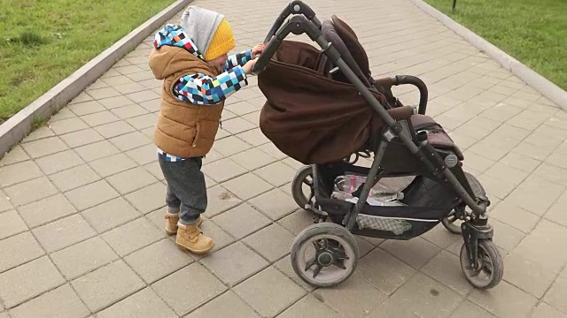 小男孩和他的婴儿车在户外散步视频下载