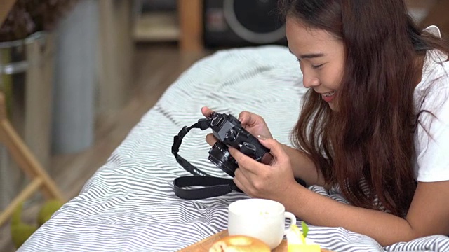 亚洲快乐的女人看着卧室里的相机，喝着咖啡和甜甜圈和水果视频下载
