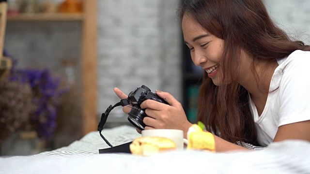 亚洲快乐的女人看着卧室里的相机，喝着咖啡和甜甜圈和水果视频下载