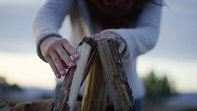 一个女人在堆木柴生火视频素材