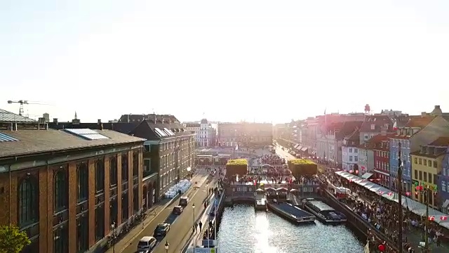 丹麦哥本哈根的背光日落镜头。尼哈芬新港运河和娱乐区的大桥。从顶部鸟瞰的视频片段。向前运动的方向。夕阳金色时光的光芒视频素材