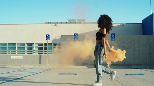 日落时分，一名年轻女子手持烟雾弹在楼顶停车场跳舞视频素材