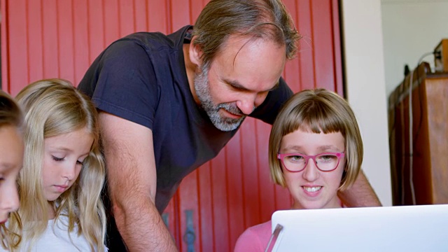 父亲和女儿在厨房里使用笔记本电脑视频素材