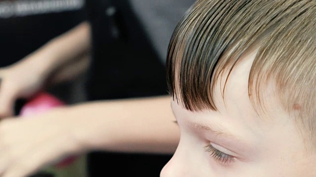 理发师近距离地为男孩梳理头发。侧视图。视频素材