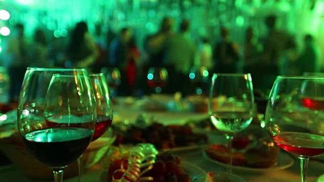 餐厅或夜总会的青年聚会，餐桌上的酒和食物，背景是跳舞的人的剪影，舞台灯光和紫色填充，浅景深的领域视频下载