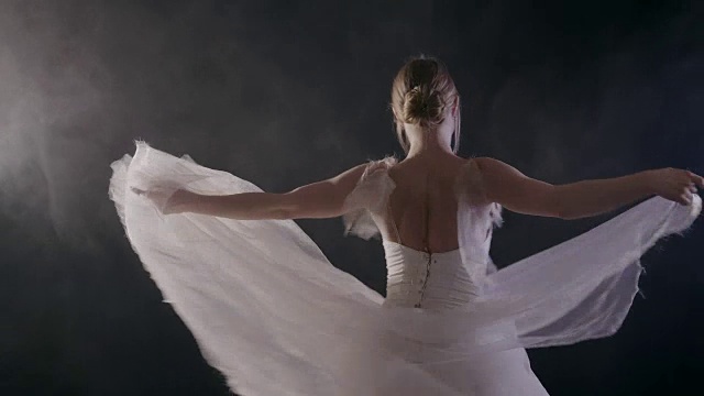 优雅性感的芭蕾舞女演员在白色芭蕾舞裙的舞蹈元素古典或现代芭蕾舞在黑色的背景与轻烟，慢动作视频素材