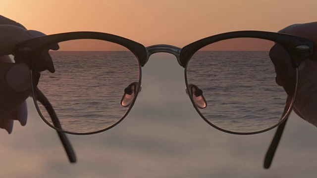 Cinemagraph -女人的手持有眼镜，蓝色的海水背景。视频下载