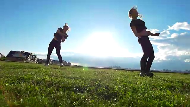 夏日日落时，活跃的年轻女子在草地上表演杂技视频素材