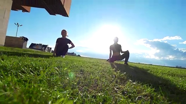 夏天日落时，年轻的女杂技演员在草地上锻炼视频下载