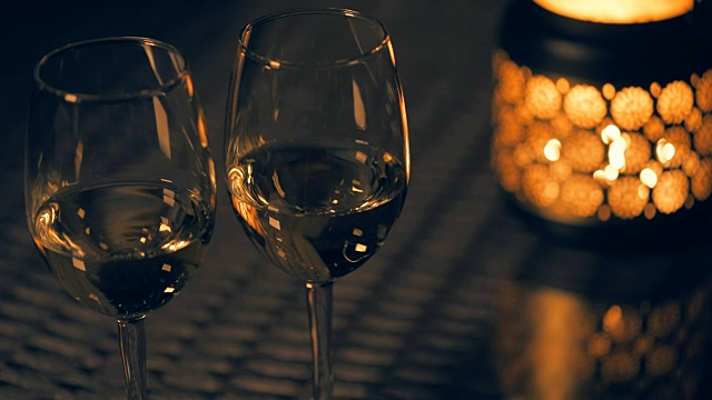 Cinemagraph -两个白葡萄酒酒杯与灯笼和点燃的蜡烛在桌子上。视频素材