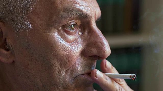 悲伤而沉思的老人抽着烟——特写肖像视频素材