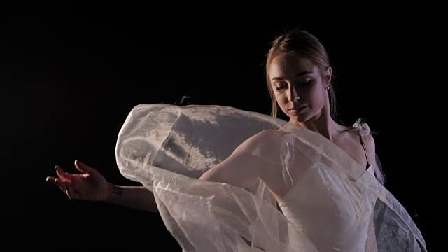 性感芭蕾舞女演员穿着古典或现代芭蕾舞元素的白色芭蕾舞裙，在聚光灯和泛光灯背景下的烟雾中旋转。慢动作视频素材