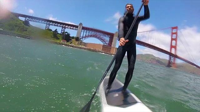 一个男人在金门大桥下直立划桨。——慢动作视频素材