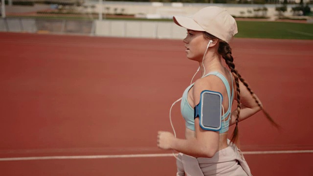 活跃的女人在运动跑道上跑步，听着音乐视频素材