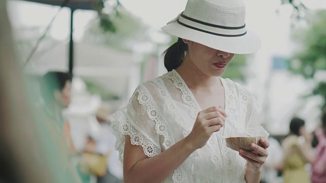 美丽的时尚女子正在吃椰子冰淇淋在市场，同时旅行在街头市场的周末视频素材