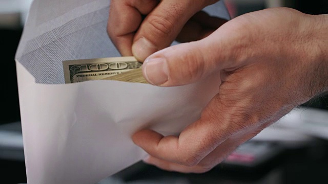 一个人拿着装着美元钞票的信封。贪污贿赂观念视频素材
