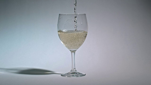 将白葡萄酒倒入玻璃杯的慢镜头。视频素材