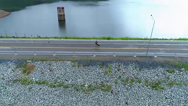 天线:一个孤独美丽的女孩沿着公路在大坝上奔跑。视频素材