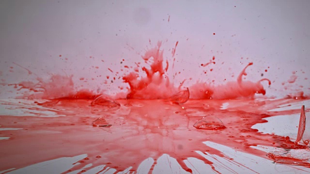 慢镜头拍摄的实验室烧杯内的红色液体正在下降和粉碎在一个坚硬的表面。视频素材