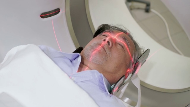 一位中年男子躺在CT扫描仪上，机器对他的身体进行成像视频下载