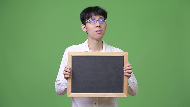 年轻的亚洲商人拿着黑板在思考视频下载