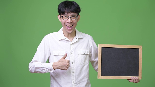 年轻的亚洲商人拿着黑板，竖起大拇指视频下载