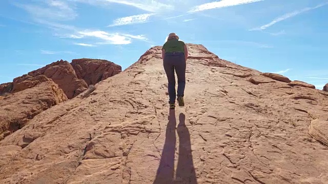 一个女人爬上巨大的红色岩石上的山视频下载