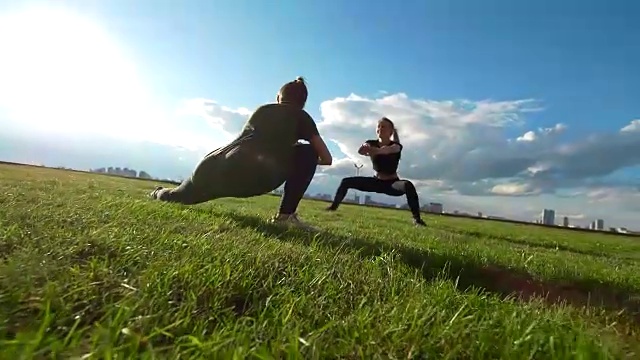 夏天日落时，年轻的女杂技演员在草地上锻炼视频下载