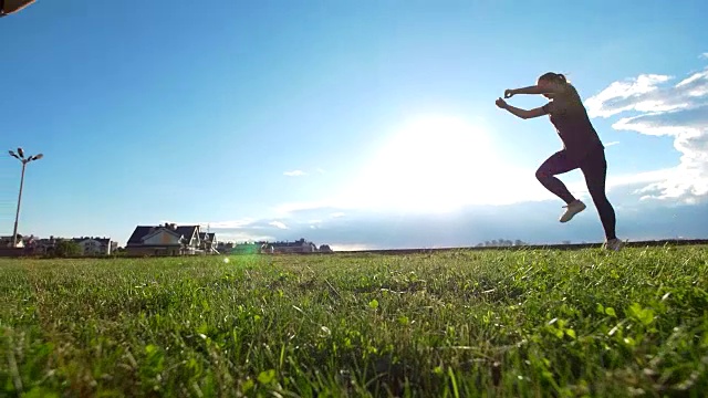 夏日日落时，活跃的年轻女子在草地上表演杂技视频素材
