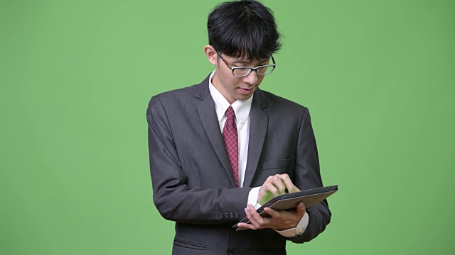 年轻的亚洲商人使用数码平板电脑视频下载