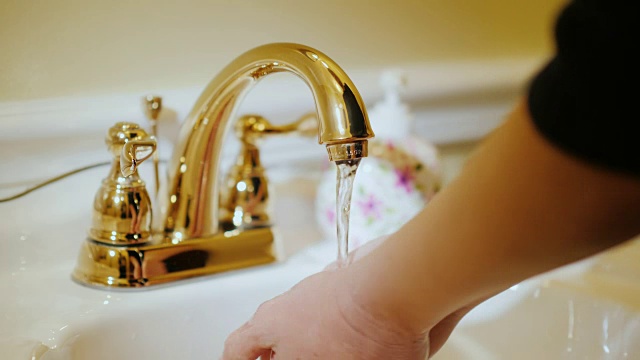 一位妇女在水龙头下洗手。水管及供水系统视频下载