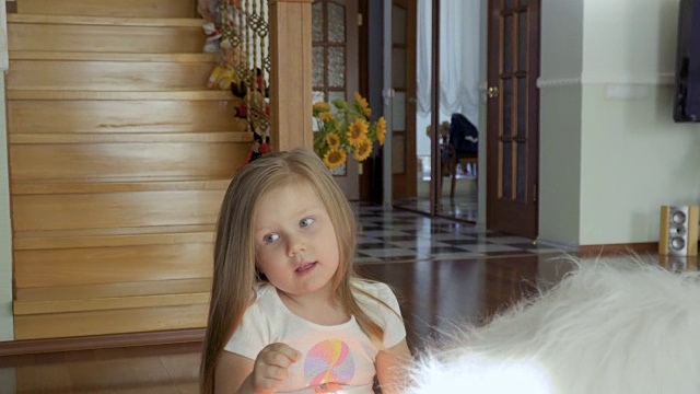 可爱的小女孩坐在家里地板上柔软的玩具上视频下载