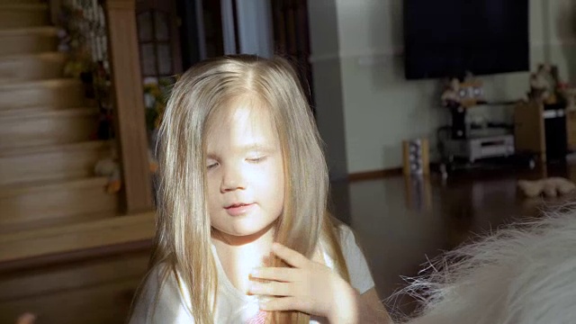 可爱的小女孩坐在大软玩具和触摸她的头发与相机调情视频下载