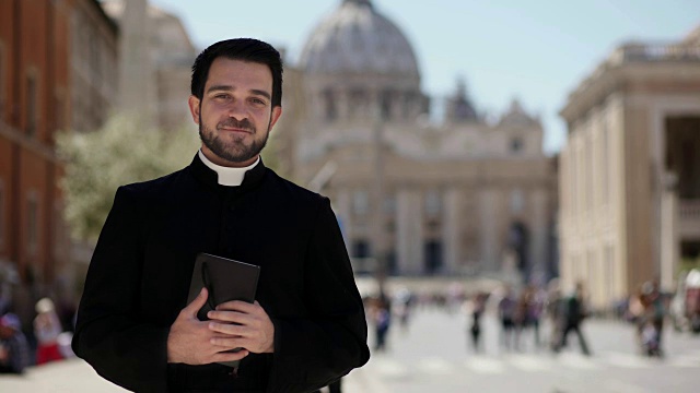 年轻的天主教牧师在镜头前微笑的肖像-圣彼得的背景视频下载