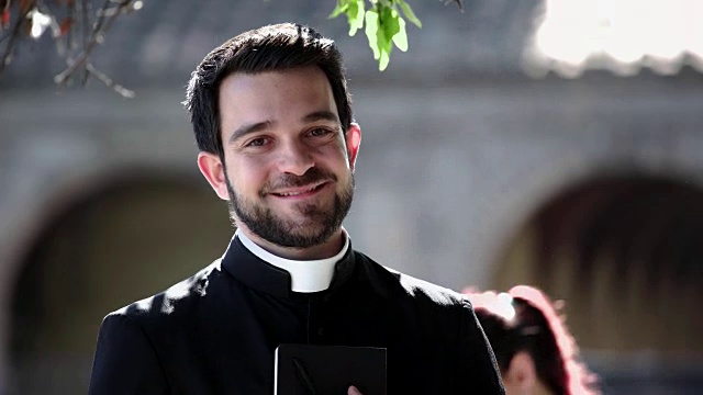 年轻的天主教神父在户外对着镜头微笑的肖像视频下载