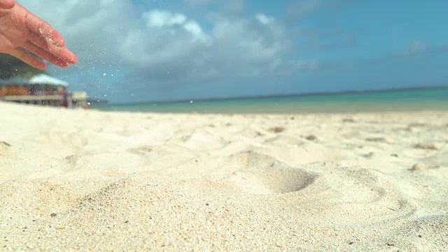 慢镜头:无忧无虑的女人在假期把沙子撒向阳光明媚的海岸。视频素材