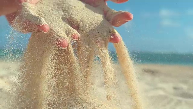 慢镜头:不知名的顽皮女孩在她温柔的手指间筛选粗糙的沙子。视频素材
