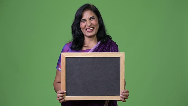 成熟快乐美丽的印度女人微笑着展示黑板视频下载