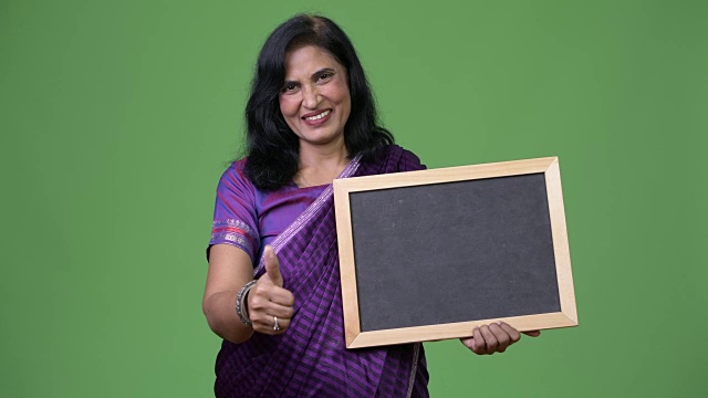 成熟快乐美丽的印度女人微笑着展示黑板，竖起大拇指视频下载