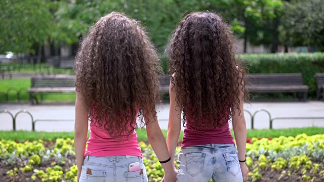 一对双胞胎姐妹手拉手，甩头发的慢镜头视频下载