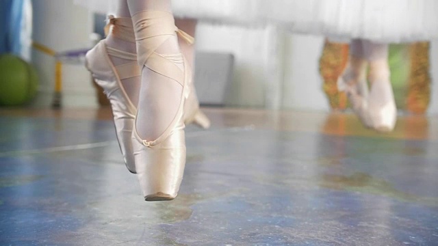 在工作室里，穿着白色芭蕾舞短裙的芭蕾舞者们穿着尖头鞋蹦蹦跳跳视频素材