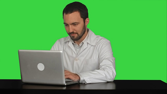 集中的男性医生使用笔记本电脑在医疗办公室的绿色屏幕，色度键视频下载