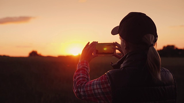 年轻的女农民在麦田上方拍摄美丽的日落视频下载