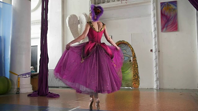 年轻美丽的芭蕾舞女演员穿着紫色的衣服在宽敞的白色工作室跳舞视频素材