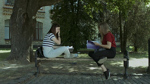 两个女大学生学习后在长椅上聊天视频素材