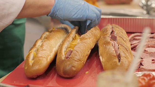手厨师把香肠片在切好的法棍面包在快餐店视频下载